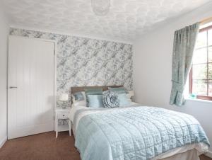 um quarto com uma cama com um edredão azul em Cae Ffynnon em Gaerwen