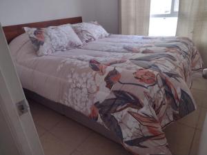 a bed with a colorful blanket and pillows on it at HERMOSO DEPTO COND MARINA SOL Lado CASINO ENJOY in Coquimbo
