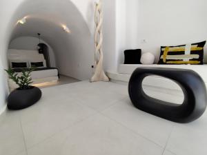 a living room with a tv on a white floor at The Magic Luxury Cave Suites in Santorini