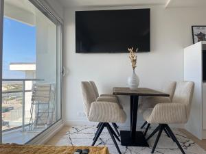 una sala da pranzo con tavolo, sedie e televisione di Le 912 appartement face mer avec balcon a Le Touquet-Paris-Plage