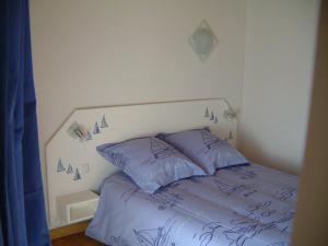 - un lit avec des oreillers bleus dans une chambre dans l'établissement L'Orangeraie, à Elne