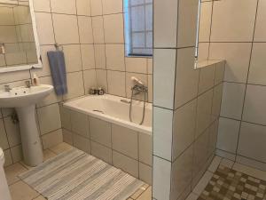 a bathroom with a bath tub and a sink at Pringle Cottage in Benoni