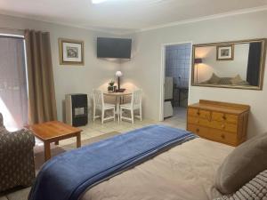 a bedroom with a bed and a table with a chair at Pringle Cottage in Benoni