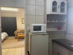 a kitchen with a microwave on top of a refrigerator at Pringle Cottage in Benoni