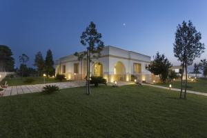 a large white building with trees in the yard at Podere40 Country Hotel in Porto Cesareo
