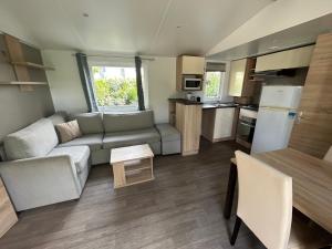 a small living room with a couch and a kitchen at Mobilhome les 3C de mimizan in Mimizan