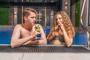 a man and woman sitting in a pool with drinks at Góralski Resort Pool & SPA in Białka Tatrzanska