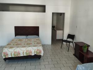a bedroom with a bed and a chair in it at Suìte Madagascar in Penha
