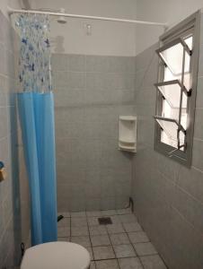 a bathroom with a toilet and a blue shower curtain at Suìte Madagascar in Penha
