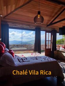 a bedroom with a bed in front of a large window at Chalé Mirante do Sol in Ouro Preto