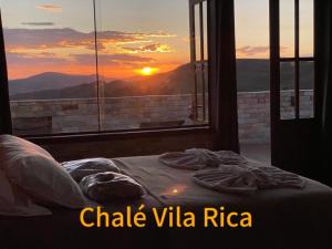 a bed in a room with a view of the sunset at Chalé Mirante do Sol in Ouro Preto
