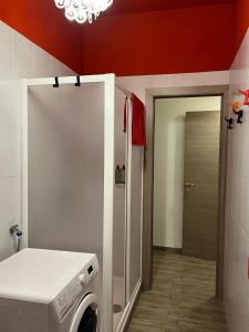 een wasmachine in een badkamer met een rode muur bij Pole Position Rho - Milano a portata di mano in Rho