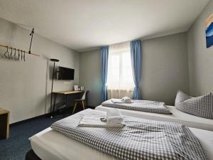 a hotel room with two beds and a desk at Novitel Pension Pliening - München Messe in Pliening