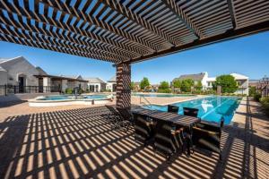 a patio with a table and chairs and a swimming pool at Just Beachy at Sand Hollow in Hurricane