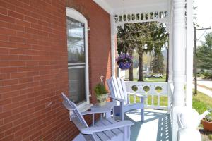 duas cadeiras azuis sentadas num alpendre ao lado de uma casa de tijolos em Cheney House Bed & Breakfast em Ashland
