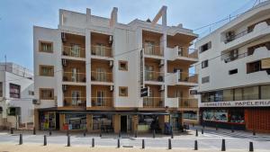 a large white building with balconies on a street at AzuLine Hostal Dinamarca in San Antonio