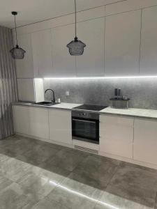 a kitchen with white cabinets and a sink and a stove at Poli House Premium in Dąbrowa