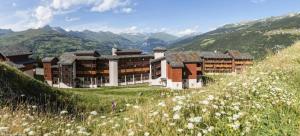 un bâtiment sur une colline avec un champ de fleurs dans l'établissement Résidence La Marelle et Le Rami - maeva Home - Appartement 3 pièces 7 perso 20, à La Plagne Tarentaise