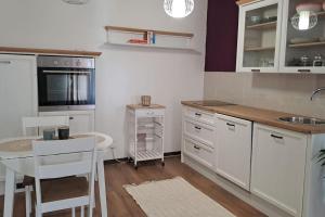 a kitchen with white cabinets and a table and chairs at Apartman Lila in Poreč +7 photos