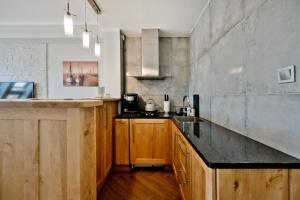 a kitchen with wooden cabinets and a concrete wall at Rodzinny Apartament we Władku in Władysławowo