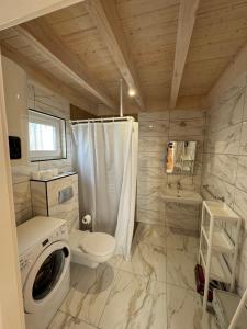 a bathroom with a toilet a sink and a washing machine at Domki letniskowe Czapli9 Domki Rewal Apartamenty in Rewal +75 photos