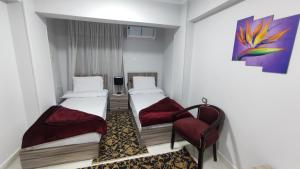 a room with two beds and a chair in it at فندق أجياد Agyad Hotel in Asyut