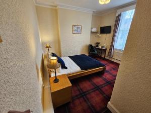 ein Hotelzimmer mit einem Bett und einem Tisch mit einer Lampe in der Unterkunft Valley Bar in Scarborough