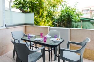a table and chairs on a patio with purple cups at Olive Garden by Golden Host in Nea Moudania