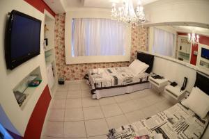 uma sala de estar com uma cama e uma televisão em Germanias Blumen Hotel em Passo Fundo