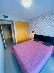 - une chambre avec un grand lit et une couette rose dans l'établissement Exclusivo piso con terraza al lado de la playa, à Lloret de Mar