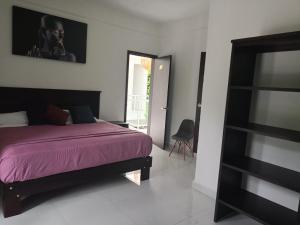 een slaapkamer met een bed met een paarse deken bij HOKAB in Cenote Azul