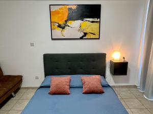 a bedroom with a blue bed with two pillows at FatCow Seaside Suites in Livadhia