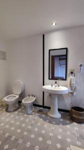 La salle de bains est pourvue de 2 toilettes, d'un lavabo et d'un miroir. dans l'établissement La Botica de 1852 Hotel, à Chascomús