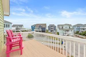 a red chair sitting on a balcony with houses at Lowe Tide in North Topsail Beach