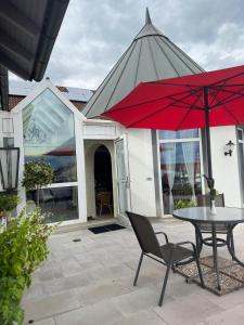 a patio with a table and a red umbrella at Dillinger Hof in Dillingen an der Donau