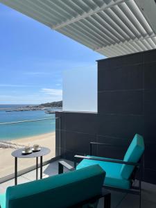 - un balcon avec des chaises bleues, une table et la plage dans l'établissement Sesimbra Blue Paradise, à Sesimbra