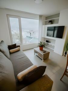 uma sala de estar com um sofá e uma janela grande em Aunaisin - Apartamento con excelentes vistas em Ushuaia