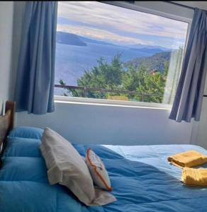 1 cama en un dormitorio con ventana grande en Aucapillan en San Carlos de Bariloche