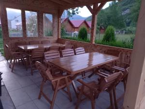 a dining room with wooden tables and chairs and windows at Breti's GuestHouse in Vusanje