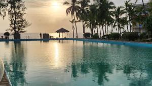 a swimming pool with palm trees and the ocean at Zuri Luxe 2BR Penthouse- Silversands Beach Malindi in Malindi