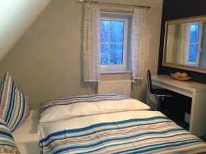 a bedroom with a bed and a desk and two windows at Ferienwohnung Hellerling in Ilsenburg