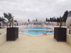 a large swimming pool with chairs and a building at KhimA XL in Hammamet Sud