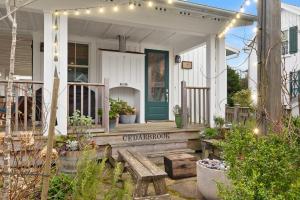 una casa bianca con portico con panchina e luci di Cedarbrook Cottage by Seabrook Hospitality a Pacific Beach