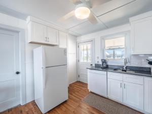 a white kitchen with white cabinets and a refrigerator at Mountains to Sea in Topsail Beach +63 photos