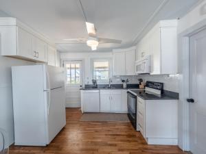 a kitchen with white cabinets and a white refrigerator at Mountains to Sea in Topsail Beach