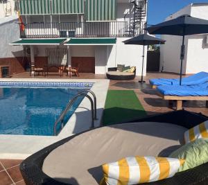una piscina con sillas y sombrillas junto a una piscina en Hevres El Capricho en Málaga