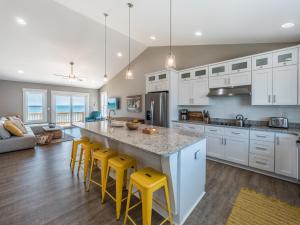 a kitchen with white cabinets and yellow bar stools at Next to Sea Gallery in Topsail Beach