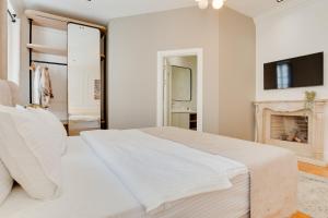 a white bedroom with a large bed and a fireplace at Atik Palace Hotel Vienna in Vienna