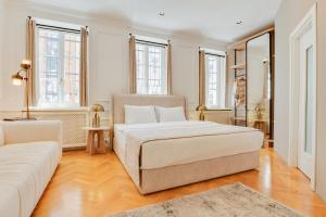 Atik Palace Hotel Vienna في فيينا: غرفة نوم بيضاء مع سرير وأريكة