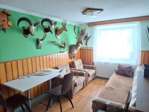 a living room with a table and some deer heads on the wall at Apartmán U jelena in Zvole
